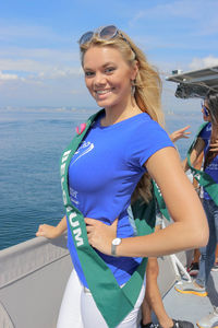 Portrait of smiling young woman standing at sea shore