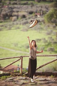 Woman throwing hat against land