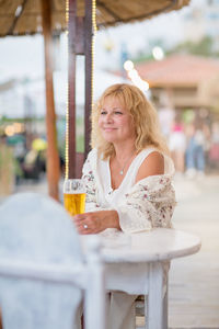 Portrait of woman drinking beer at beach cafe