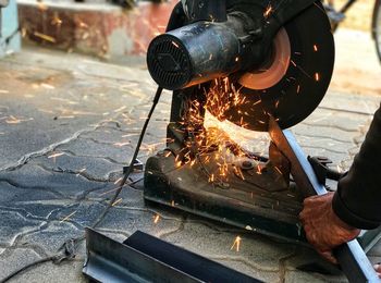 Cropped hand of man cutting metal with electric saw