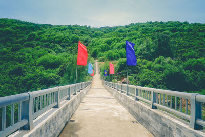 Multi colored flag against trees and plants against sky