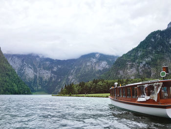 Boat sailing on lake by mountains against sky