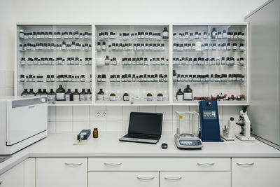 Laptop by device and containers arranged in chemist shop