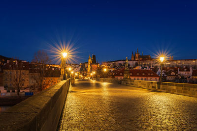 Illuminated city by river against sky at night