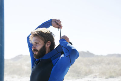 Man wearing swimwear at beach against clear sky during sunny day