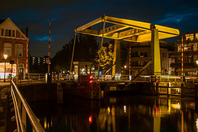 Illuminated bridge over river against sky at night