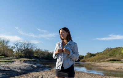 Young woman using smart phone against sky