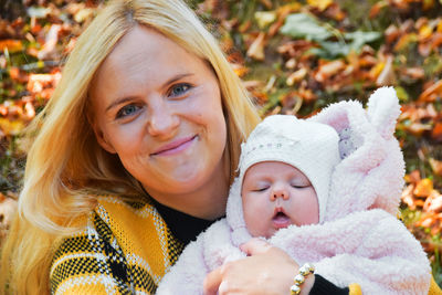 Little girl newborn with her mother in park during fall season hugging and cuddling