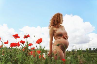Rear view of pregnant woman standing on field against sky