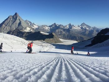 People on snowcapped mountains against sky