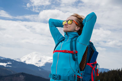 Side view of young man photographing while standing on snowcapped mountain