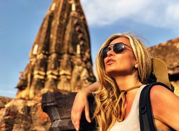 Low angle view of mature woman wearing sunglasses against building