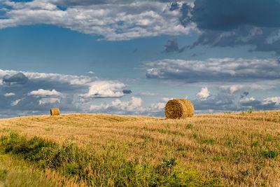Hay bales on field against sky