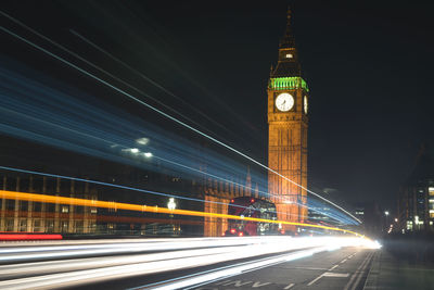 Light trails on road by big ben at night