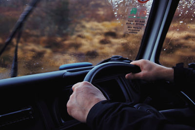 Male hands on the steering wheel of a vehicle