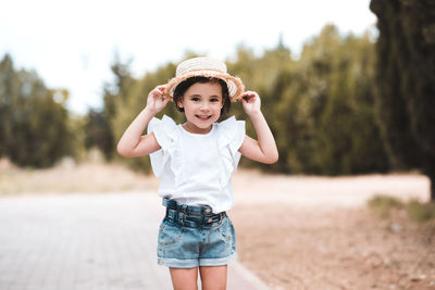 Smiling baby girl 3-4 year old wearing hat and summer clothes outoodrs. looking at camera. childhood