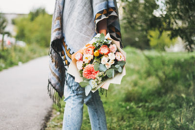 Low section of woman standing by flowering plants