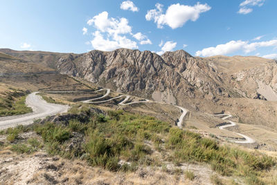 Scenic view of road by mountains against sky