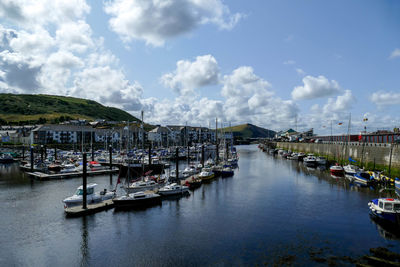 Boats moored in harbor against sky in city