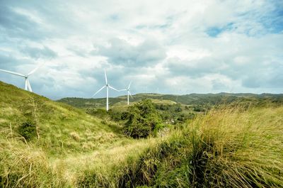 Wind turbines on land against sky