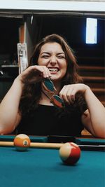 Portrait of young woman holding ball while sitting on table