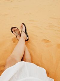 Low section of woman relaxing on sand