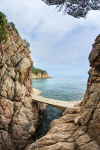 Rock formation by sea against sky