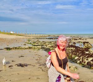 Portrait of woman walking at beach against sky