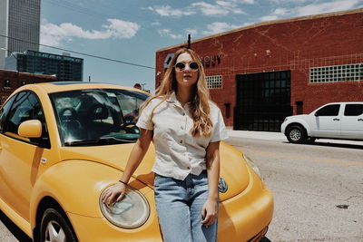 Young woman wearing sunglasses standing by car