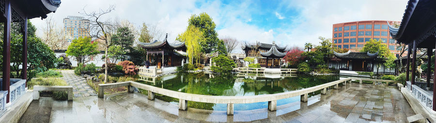 Panoramic view of swimming pool by building against sky