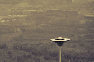 Telephone pole on land against mountain