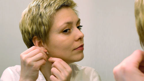Close-up of woman wearing earring reflecting on mirror