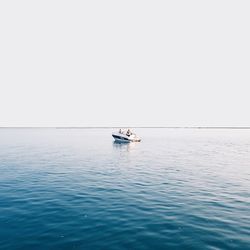 Boat sailing in sea against clear sky