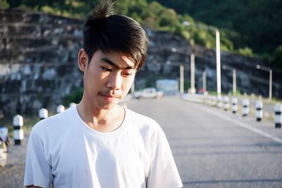 Thoughtful young man looking down while standing on street