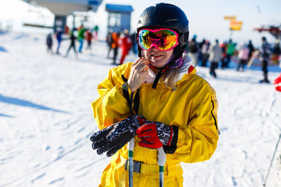 Woman wearing ski goggles while standing on snow covered land