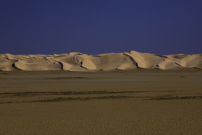 Scenic view of desert against clear blue sky