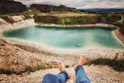 Low section of man on rock by lake