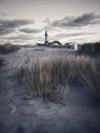 Lighthouse on field against sky during winter