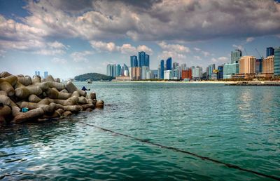 Sea by cityscape against sky