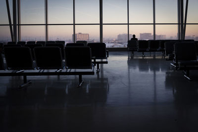 Chairs and tables at airport against sky during sunset