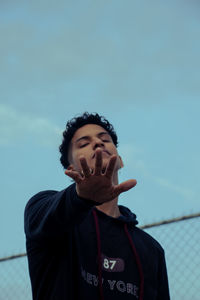 Portrait of young man standing against sky