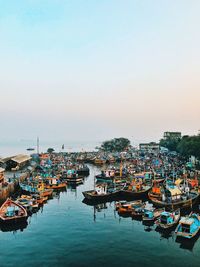 Boats moored at harbor against clear sky