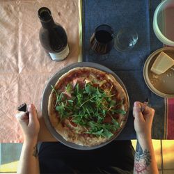 Cropped image of hand with pizza and wine on table