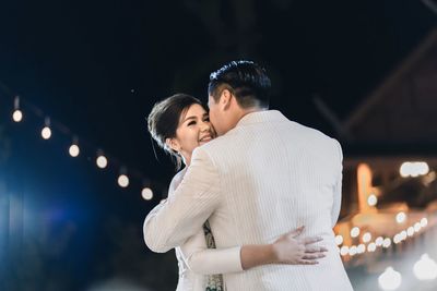 Young couple standing outdoors at night