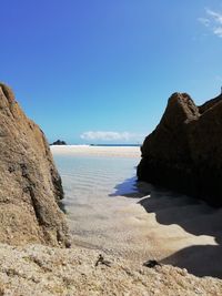 Rock formations on beach against blue sky