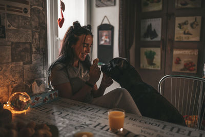 Woman with dog sitting on table at home