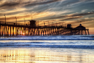 Pier over sea against sky during sunset