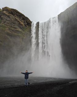 Rear view of man standing against waterfall