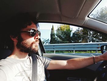 Side view of handsome bearded man driving car 