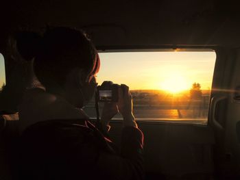 Young woman photographing while traveling in car